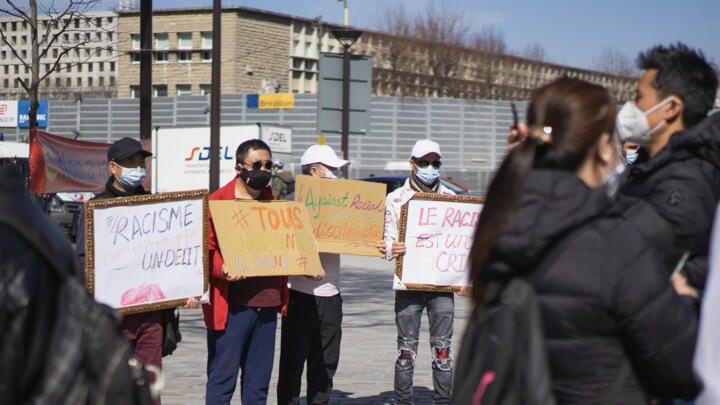 People hold signs to protest racism outside a court building in Paris where five men went on trial for tweeting threatening, hateful messages directed at Chinese people on March 24.